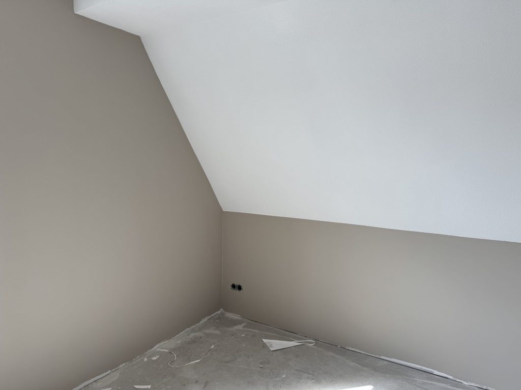 Kamer met schuin plafond en strak afgewerkte wanden, de vloer nog afgedekt met folie